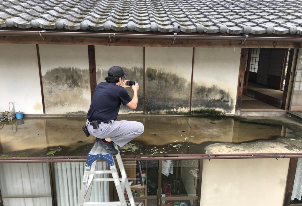 浸水被害の高さや範囲をスマートフォンで撮影して記録している様子