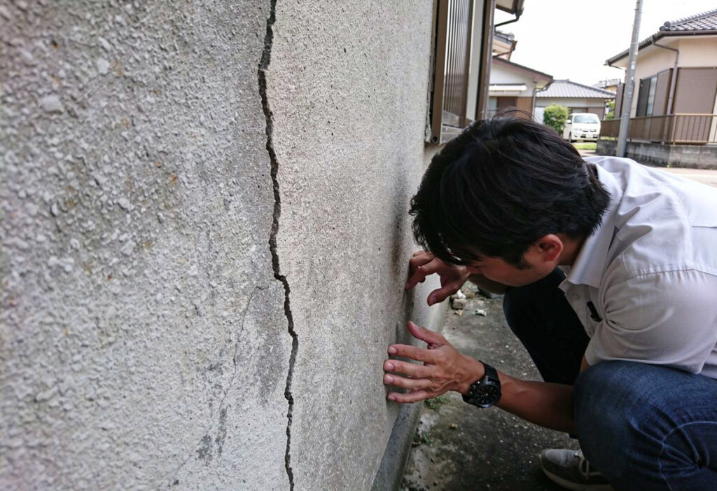 日本の戸建住宅の外壁にできたひび割れを近づいて確認している様子
