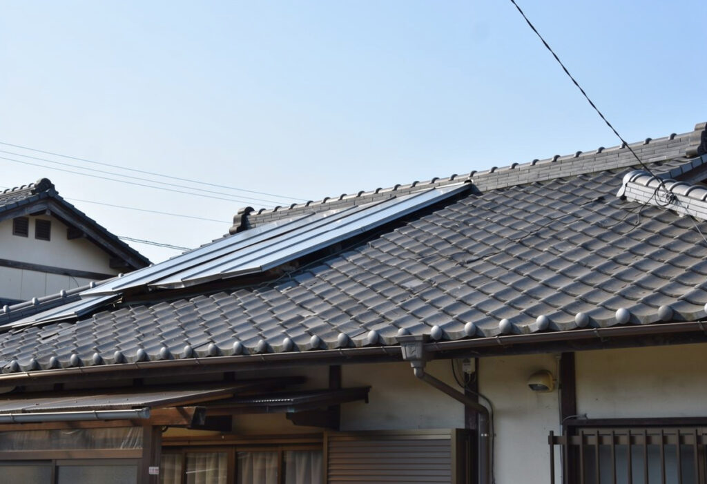 地震後に瓦のズレや棟板金の浮きがないか地上から屋根を確認している様子